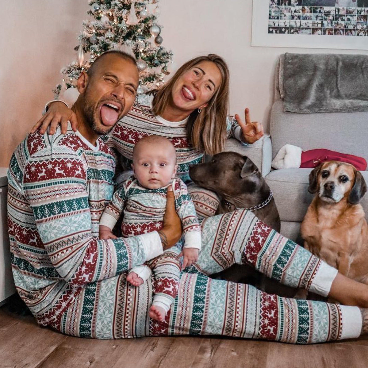 Family in matching pajamas with two dogs in a living room decorated for Christmas.